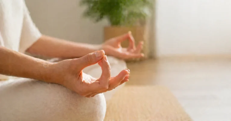Deux mains formant le Chin mudra, geste sacré des mudras mains énergie, sur fond naturel beige et bois clair