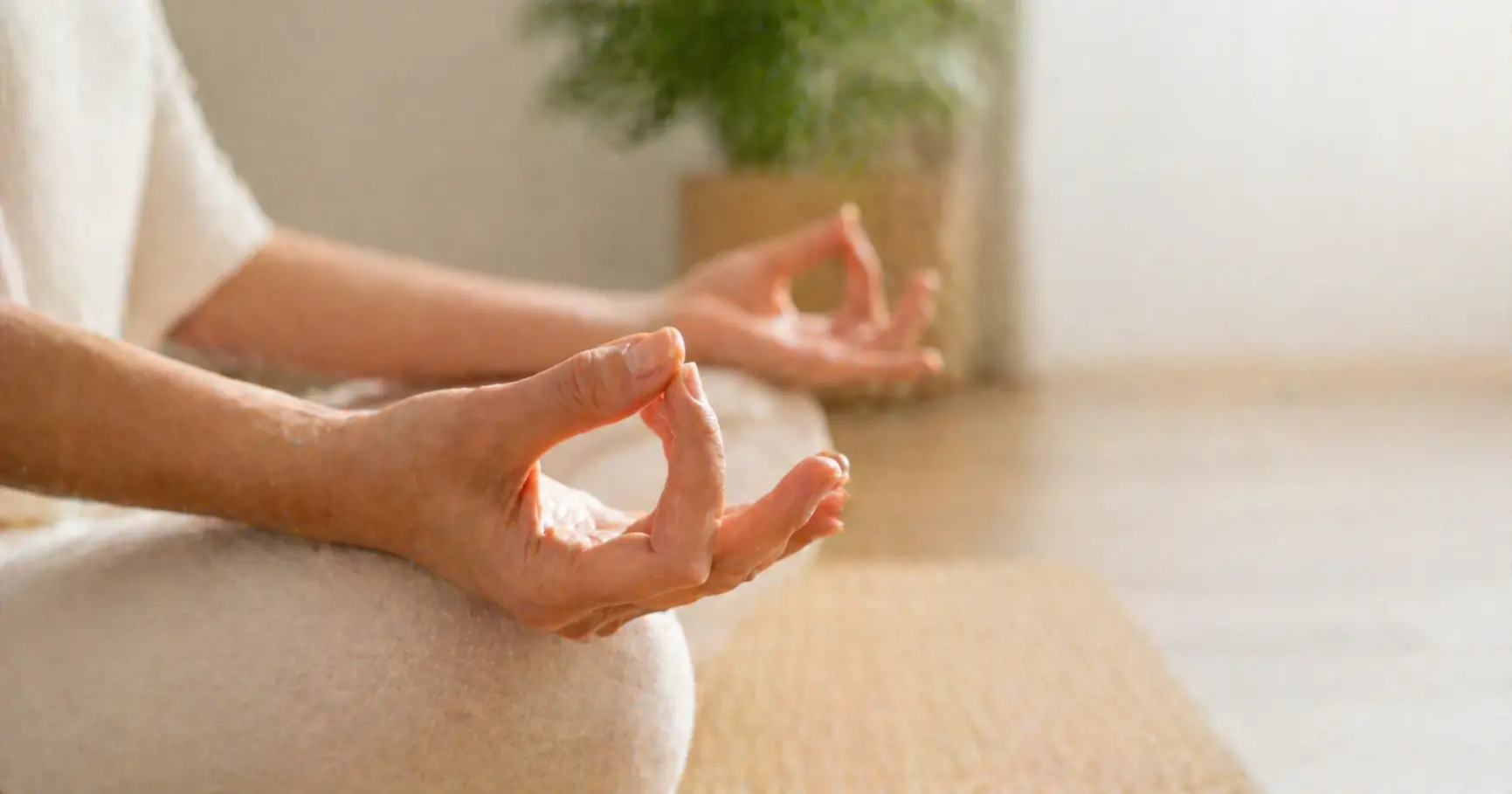 Deux mains formant le Chin mudra, geste sacré des mudras mains énergie, sur fond naturel beige et bois clair