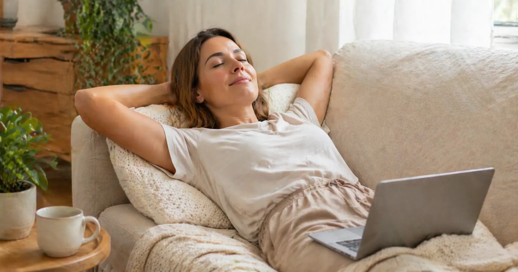 Personne allongée confortablement chez elle avec un ordinateur portable ouvert pour recevoir un soin énergétique à distance