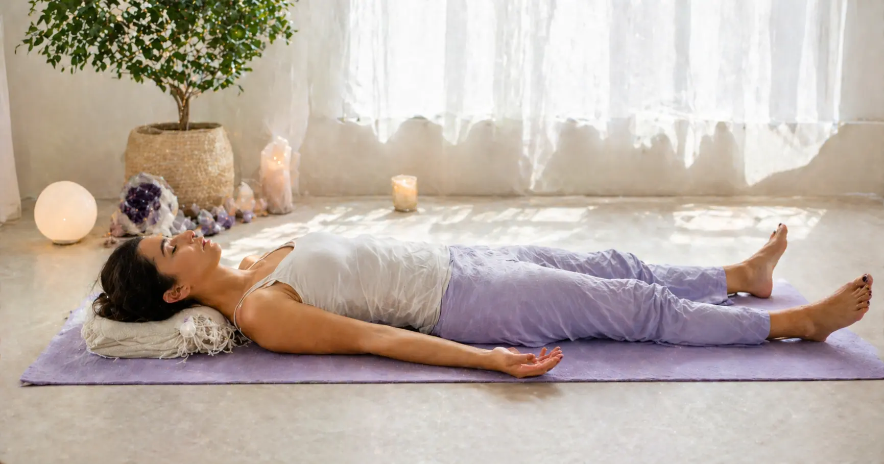 Femme allongée sur un tapis de yoga lavande pratiquant le body scan méditation corps, yeux fermés, état de relâchement total